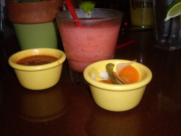 Strawberry margarita flanked by salsa and spicy carrots